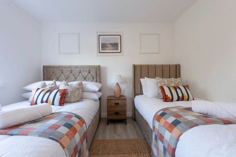 Twin bedroom with two beds, upholstered headboards, patterned throws and decorative pillows