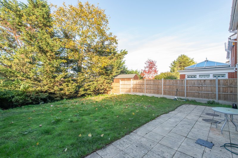 Spacious back garden with patio, lawn, wooden fence and garden shed