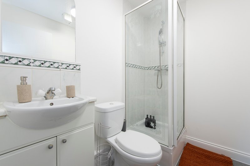 Modern bathroom with curved sink, toilet, glass shower enclosure and white tiles