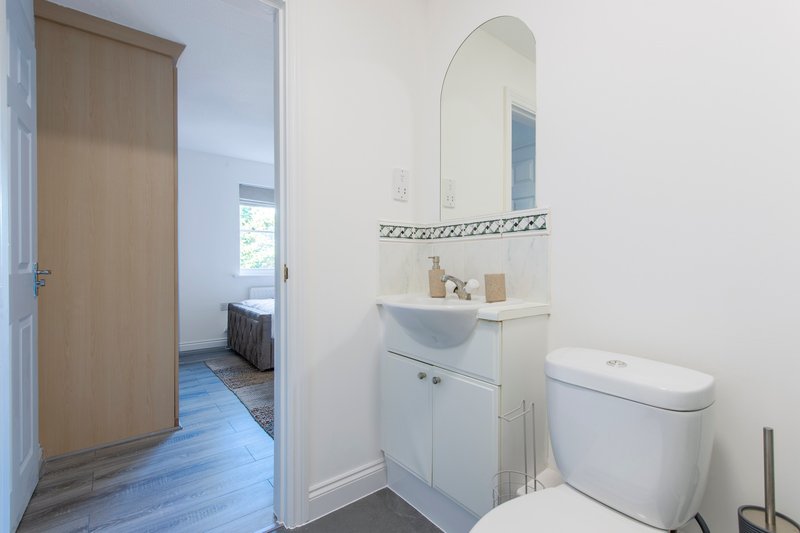 Modern bathroom with white vanity, oval mirror, toilet and blue tile flooring