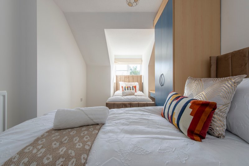 Modern bedroom with twin beds, striped cushions, and skylight overlooking hallway