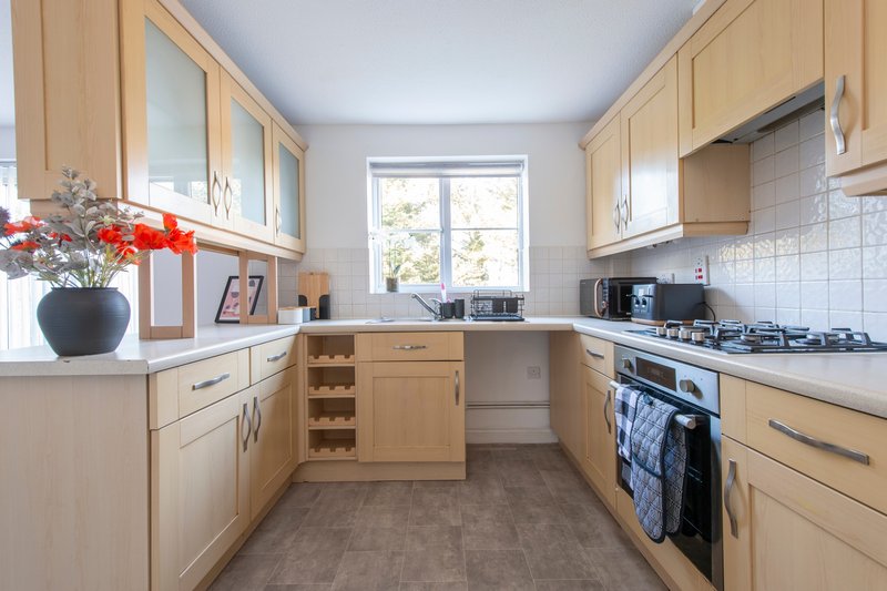 Modern kitchen with light wood cabinets, white countertops, gas hob and integrated appliances