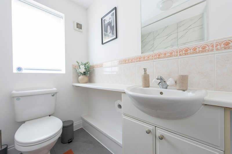 Clean bathroom with white sink, toilet, tiled walls and small window