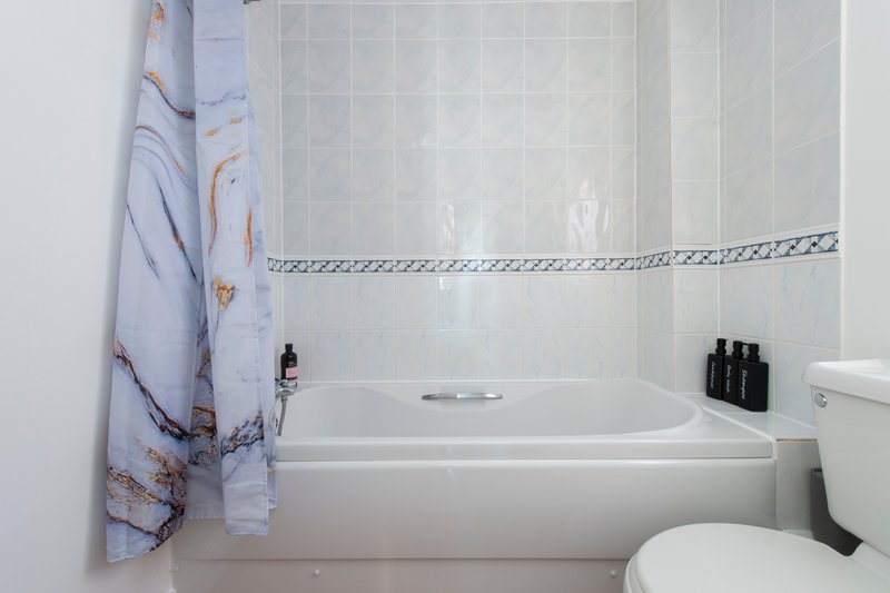 Bathroom with white subway tiles, bathtub, toilet, and patterned shower curtain