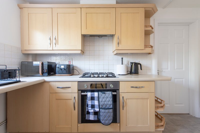 Modern kitchen with wooden cabinets, gas hob, oven and integrated appliances