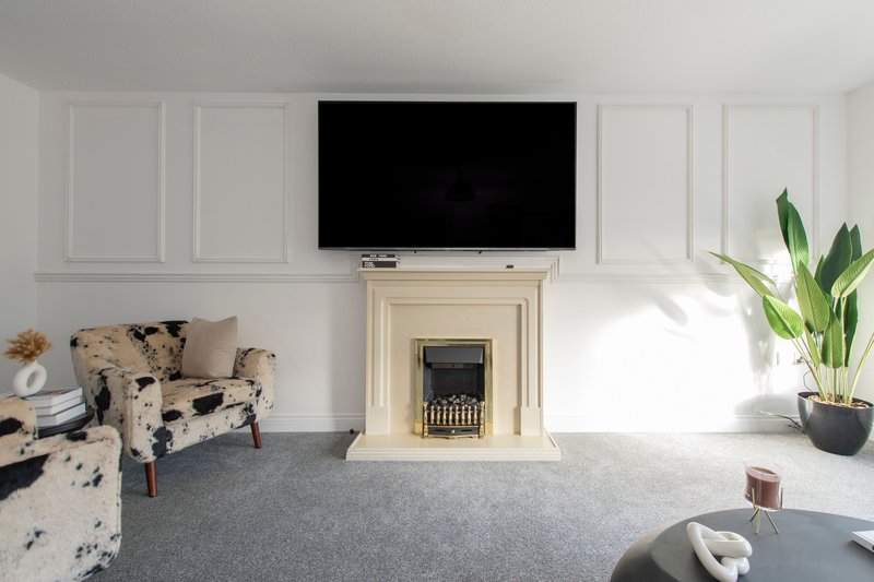 Bright living room with fireplace, wall-mounted TV, patterned armchair and potted plant