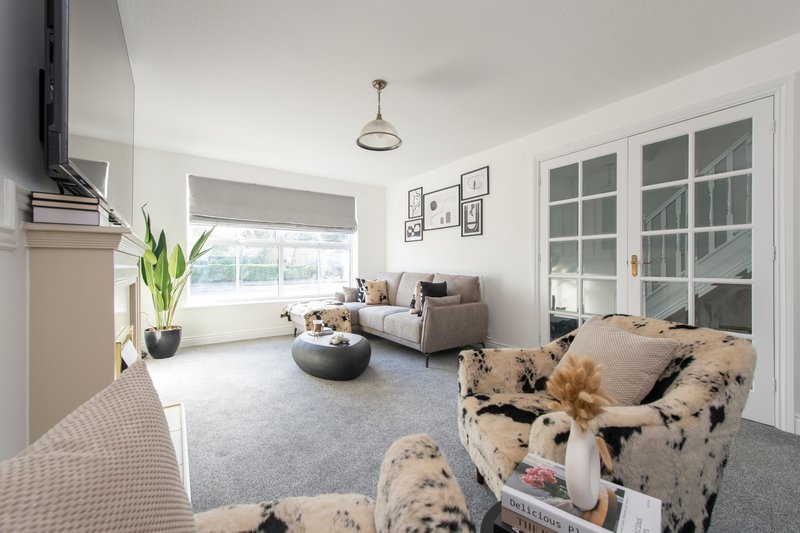 Bright living room with patterned armchairs, sofa, coffee table and French doors