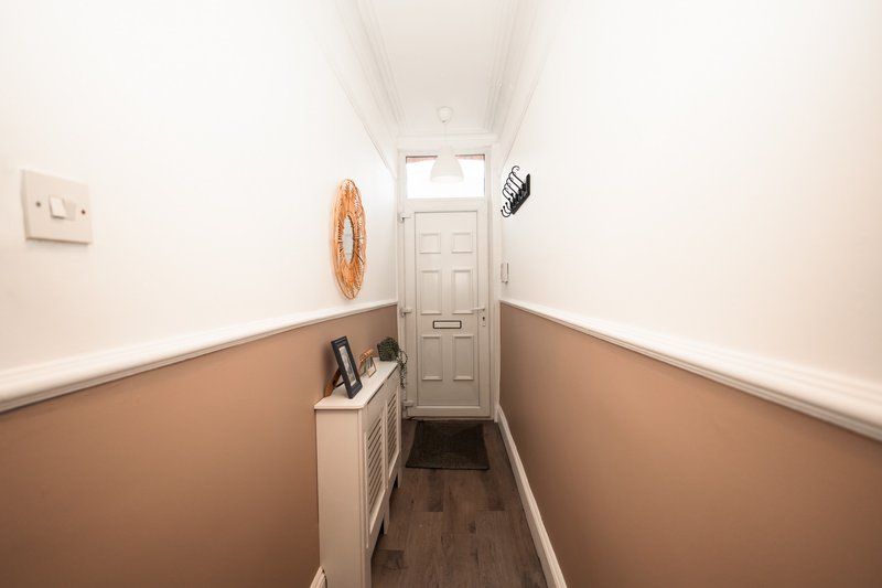Narrow hallway with two-tone painted walls, wooden floor, and closed door at end