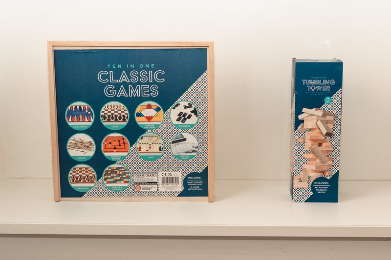 Shelf displaying two boxed board games and wooden block tower game
