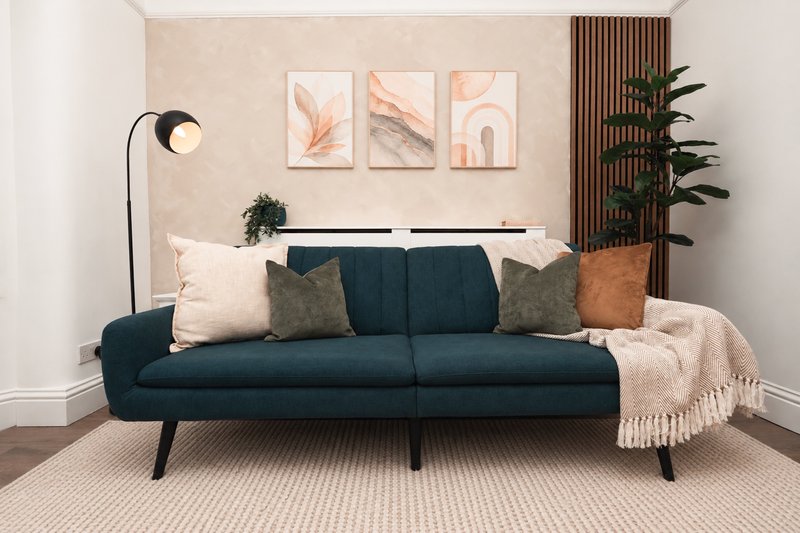 Living room with dark blue sofa, decorative cushions, arc lamp, and wall art