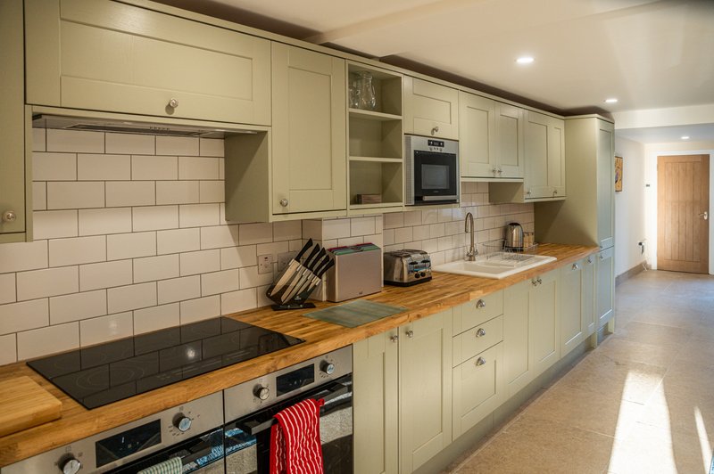Modern cream kitchen with wooden countertops, subway tile backsplash, and stainless steel appliances