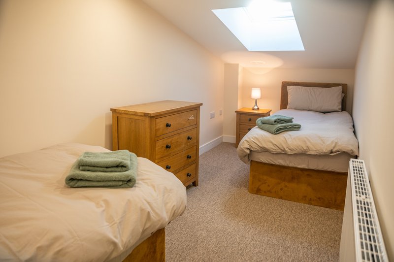 Twin bedroom with two beds, wooden furniture, skylight window and bedside lamp
