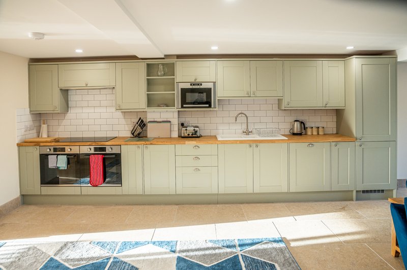 Modern kitchen with cream cabinets, wooden countertop, subway tile backsplash and built-in appliances