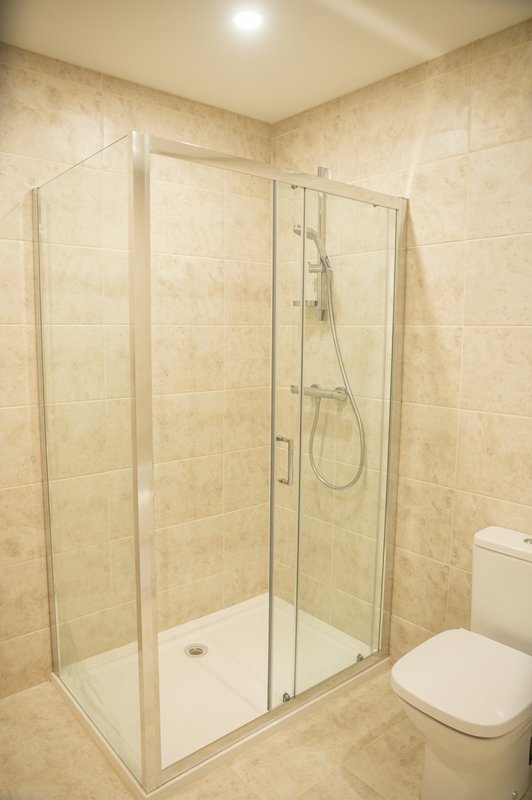 Modern bathroom with walk-in shower enclosure, tiled walls, and white toilet