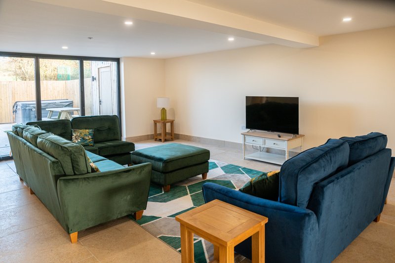 Spacious living room with green and blue sofas, TV, wooden coffee table and patio doors