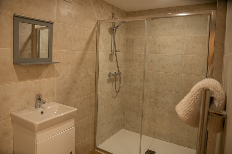 Modern bathroom with walk-in shower, white vanity sink, mirror and towel rail