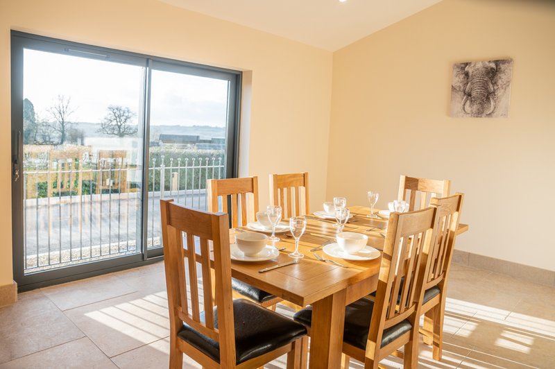 Dining room with wooden table, chairs, and glass doors opening onto a balcony