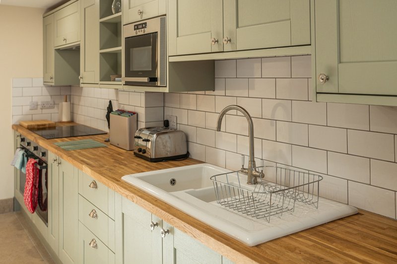 Kitchen with cream cabinetry, wooden worktops, white subway tile backsplash and integrated appliances