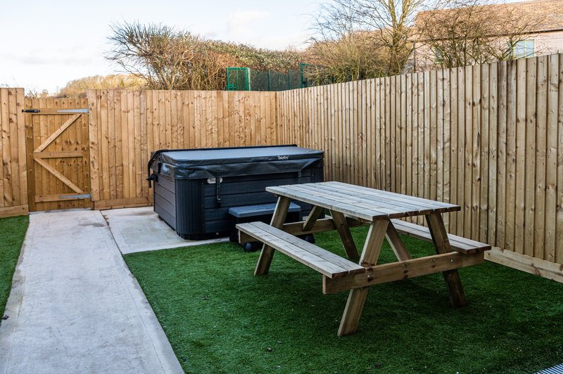 Garden area with wooden fencing, picnic table, hot tub and paved patio