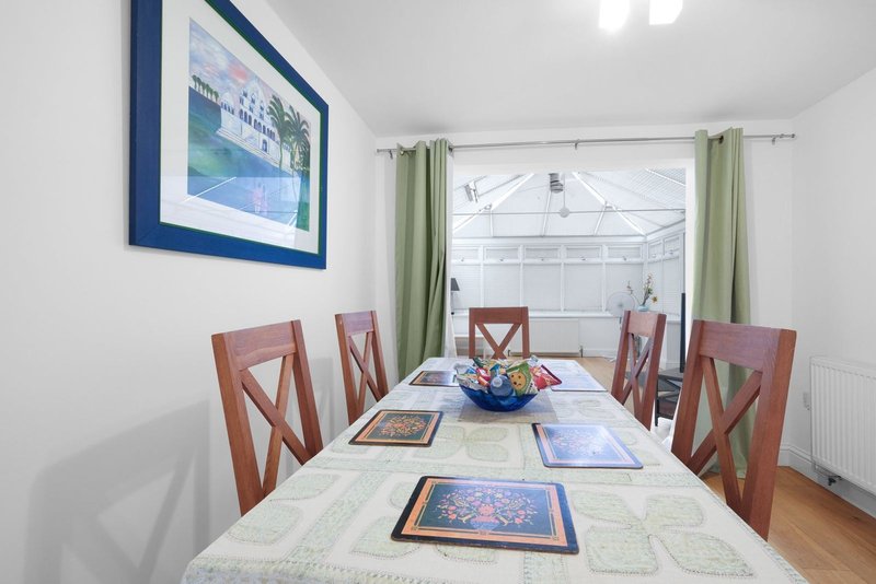 Dining room with wooden table, four chairs, framed artwork on walls and table surface