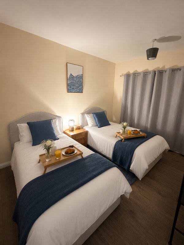 Twin bedroom with two single beds, navy bedding, wooden bedside tables and warm lighting