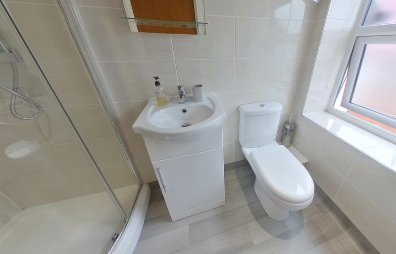 Modern bathroom with sink vanity, toilet, shower enclosure and window