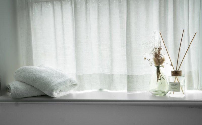 Bright windowsill with cushion, dried flowers in glass vases and diffuser