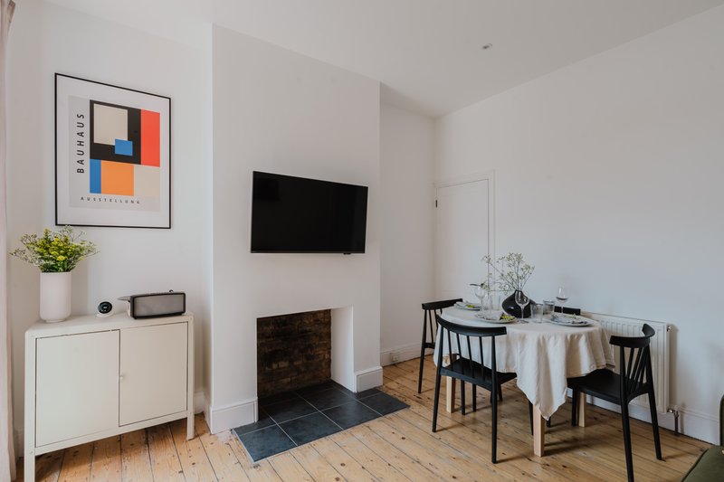 Modern living room with fireplace, wall-mounted TV, dining table, and contemporary artwork