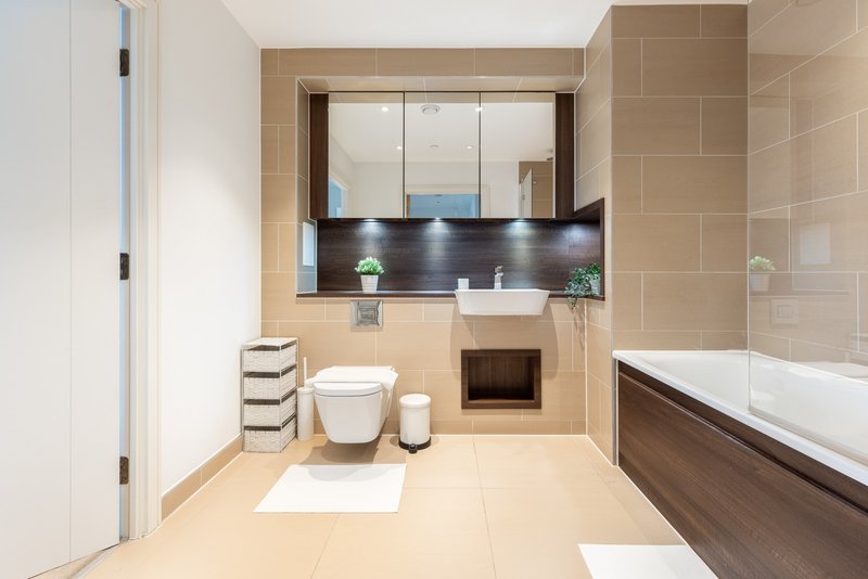 Modern bathroom with large mirror, toilet, sink, bathtub and beige tile flooring