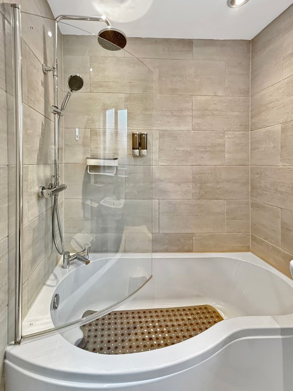 Modern bathroom with curved bathtub, glass shower enclosure, and tiled walls