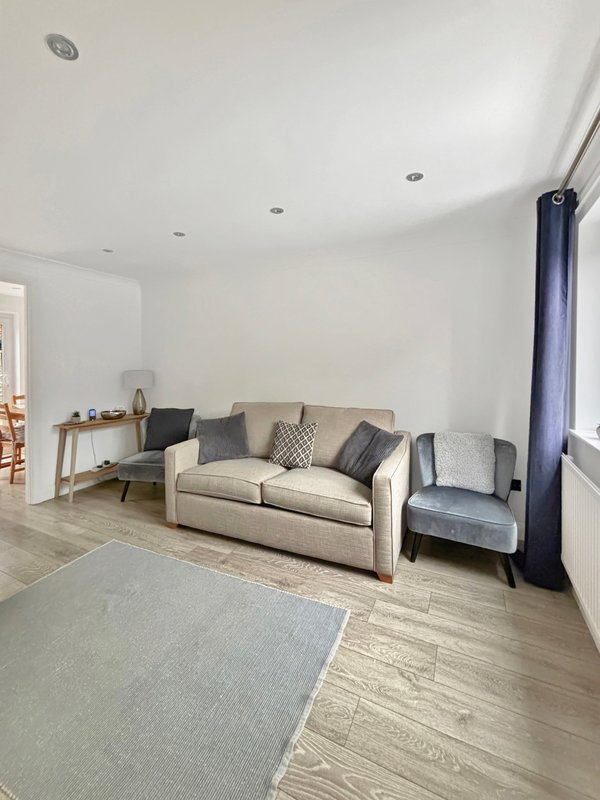 Bright living room with neutral sofa, armchair, wooden floor and blue curtains