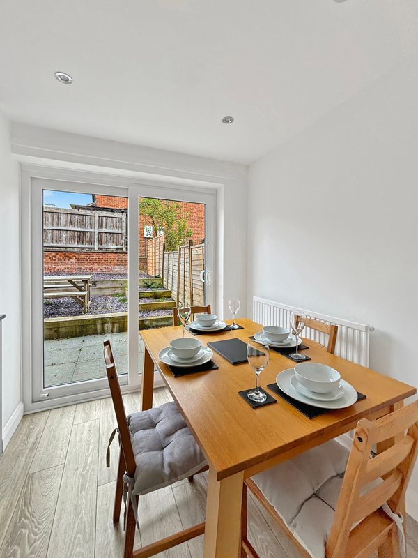 Dining room with wooden table, place settings, and glass doors opening to garden view