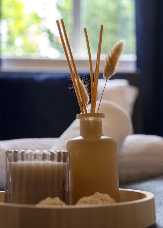 Home décor arrangement with reed diffuser, candle and tray on side table