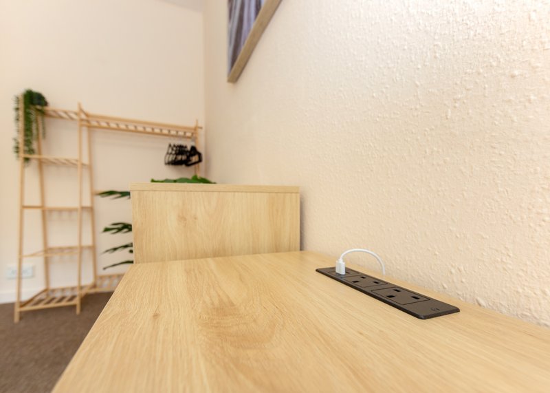 Minimalist wooden desk and shelving unit in bright, unfurnished room with white walls