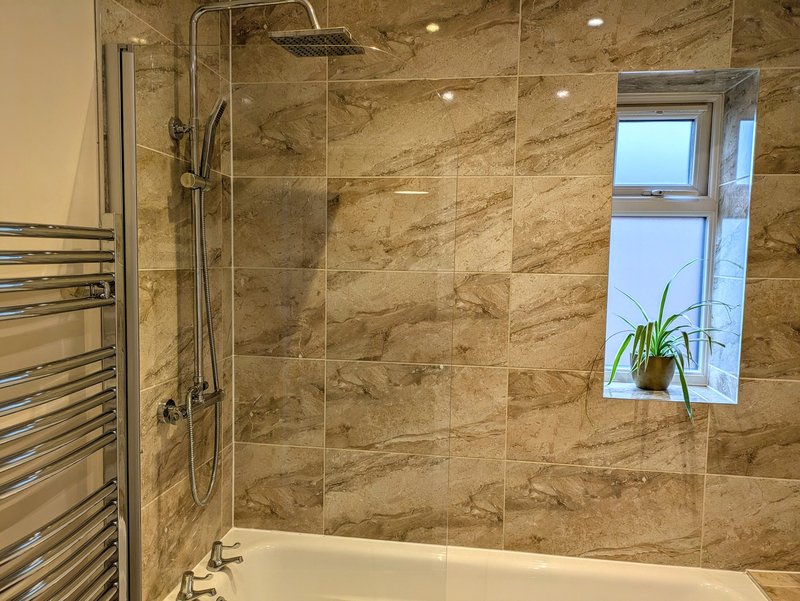 The modern shared bathroom features a large shower over the bath with heated towel rail. Clean, practical and well-equipped including complimentary toiletries.