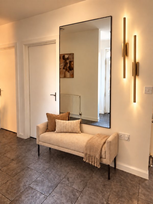 Modern entryway with upholstered bench, large mirror, and contemporary wall sconces