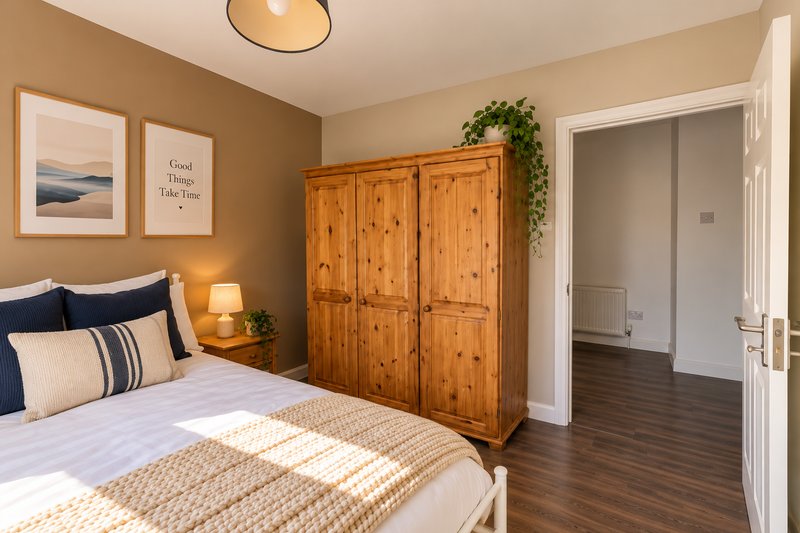 Bedroom with double bed, wooden wardrobe, wall art, and dark wood flooring
