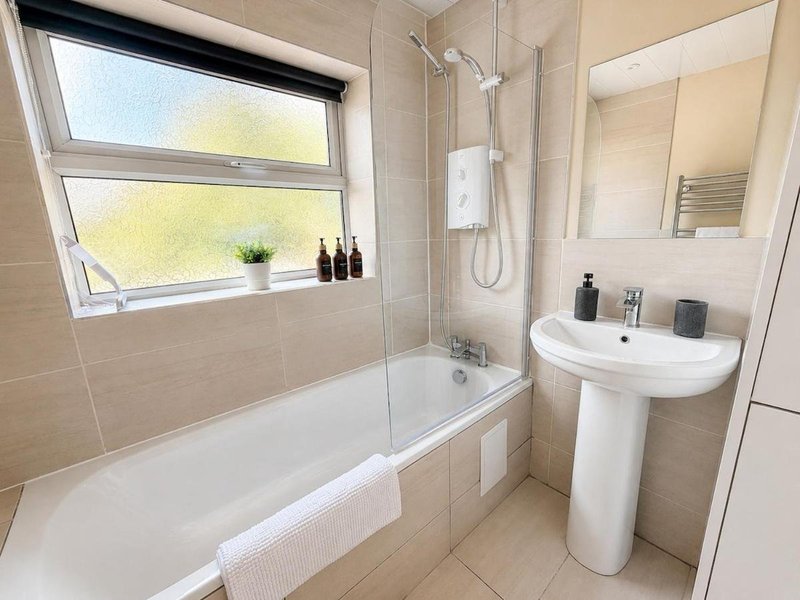 Modern bathroom with bathtub, pedestal sink, walk-in shower and large window