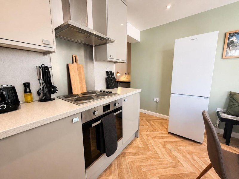 Modern kitchen with white cabinetry, stainless steel appliances, wooden countertops and herringbone flooring