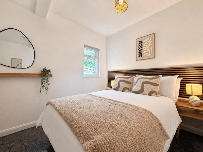 Modern bedroom with double bed, striped headboard, round mirror and pendant light