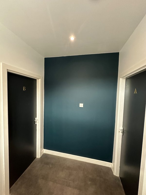 Hallway with teal accent wall, two dark doors labeled A and B, gray flooring