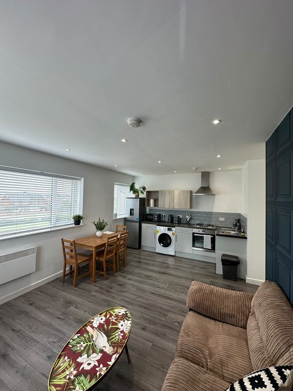 Open-plan kitchen and living area with dining table, sofa, and modern appliances