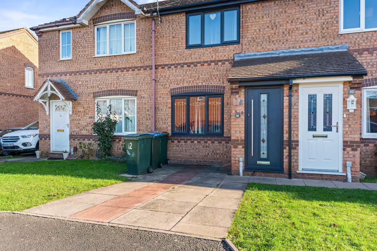Brick terraced house with driveway, front garden, and multiple entrance doors