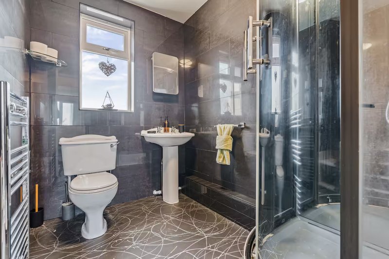 Modern bathroom with toilet, pedestal sink, shower enclosure and heated towel rail