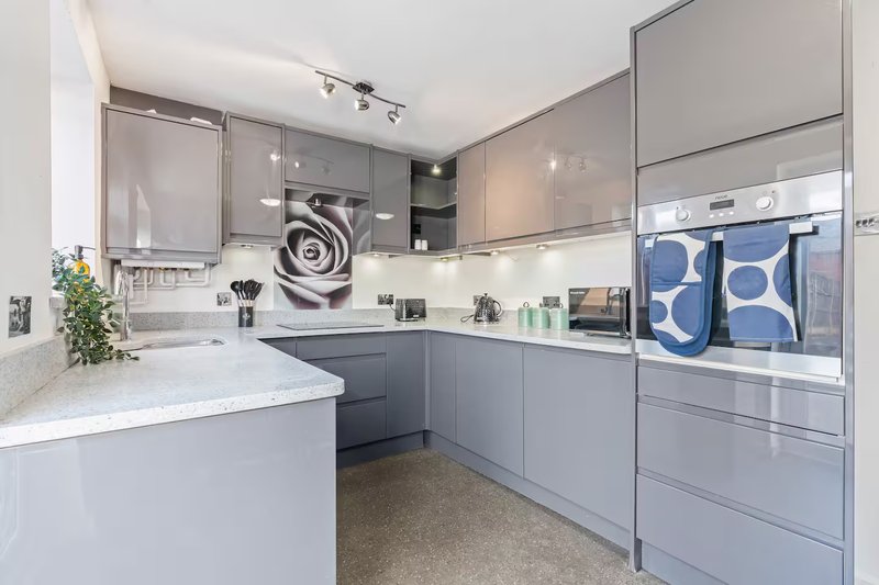 Modern kitchen with grey cabinetry, white countertop, integrated appliances and island