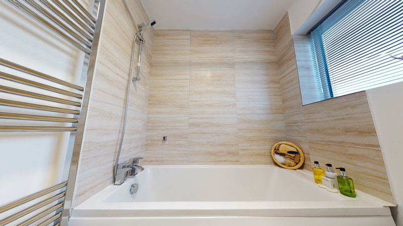 Modern bathroom with soaking tub, wood-tile surround, heated towel rail and window