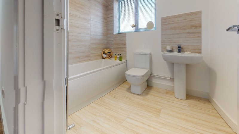 Modern bathroom with walk-in shower, toilet, pedestal sink and wooden flooring