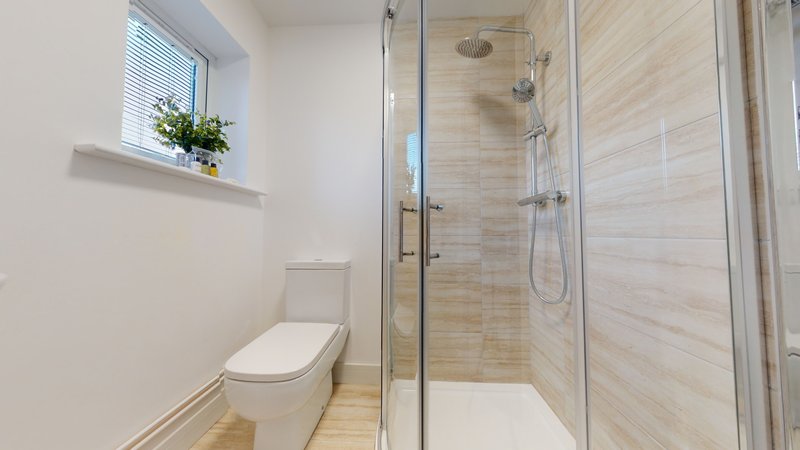 Modern bathroom with toilet, walk-in shower, and small window with plant