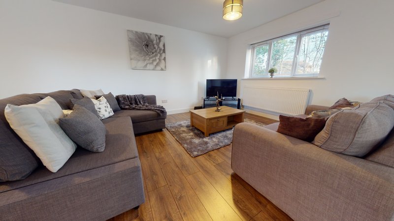 Spacious living room with two upholstered sofas, wooden coffee table, and large windows