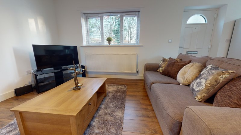 Living room with brown sofa, wooden coffee table, TV on stand, and large windows